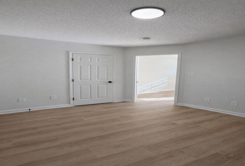 Bright interior space featuring wood-finish flooring, white painted walls, and a contemporary flush-mount ceiling light
