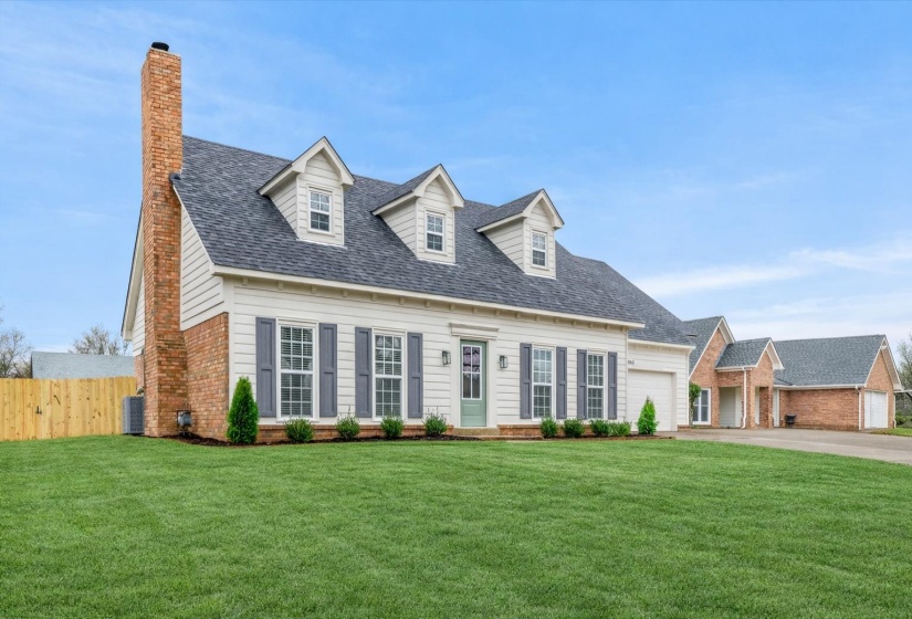 Traditional-style residence featuring a combination of brick and siding, a dark shingle roof, and multiple dormer windows