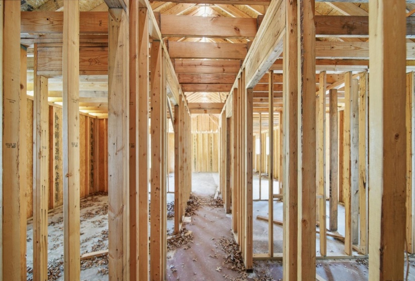 New construction framing showcasing structural wood studs, exposed ceiling joists, and subflooring