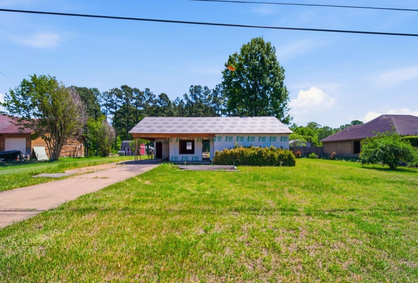 Ranch-style residence featuring a carport, front yard, and mature shrubs