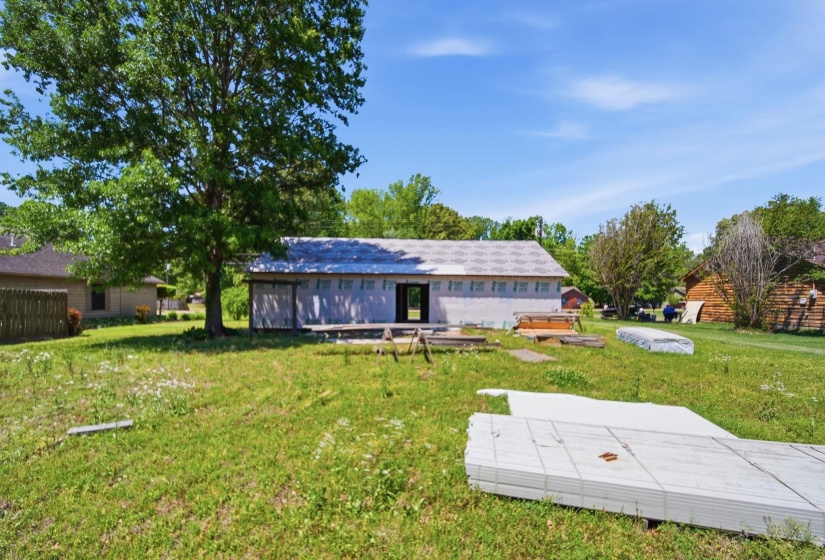 Building under construction featuring a shingled roof and exposed wall sheathing