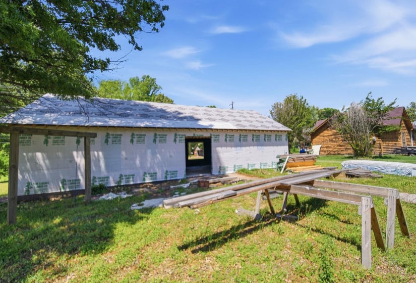 New construction featuring a partially completed exterior with a roof structure, building wrap, and exposed framing