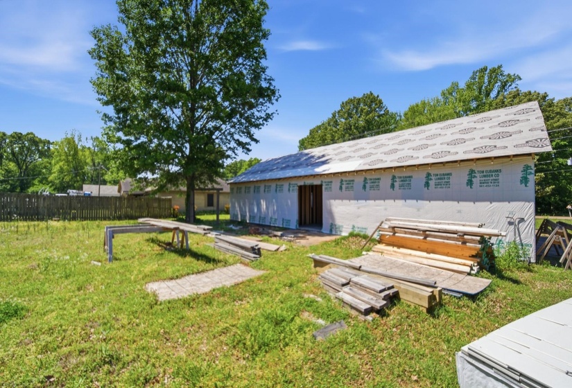 New construction structure featuring an unfinished exterior, exposed roof sheathing, and a partially framed opening