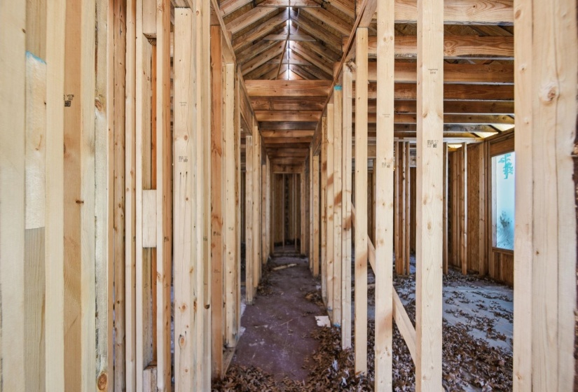 New construction framing showcasing structural wood studs, exposed ceiling joists, and a rough subfloor