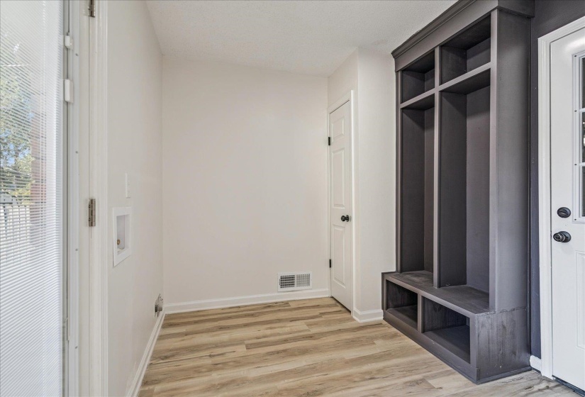 Mudroom space featuring built-in charcoal-finished cabinetry with open shelving and bench storage