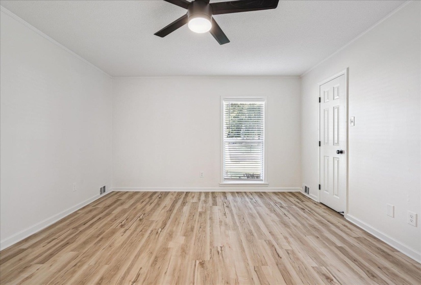Room featuring wood-finish flooring, crisp white walls, and a window with blinds
