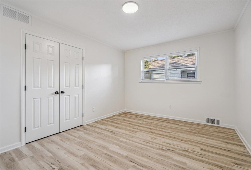 Bright room featuring wood-finish flooring, a double-door closet, and a white ceiling light fixture