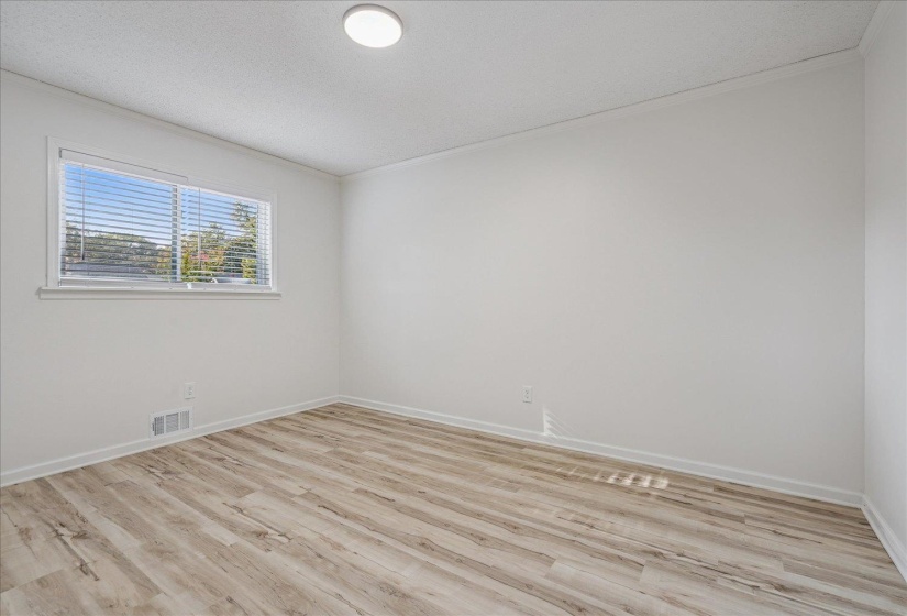 Bright interior room featuring wood-finish flooring, white walls, and a window with horizontal blinds