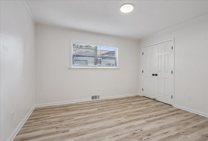 Room featuring wood-finish flooring, white walls, and a window with blinds