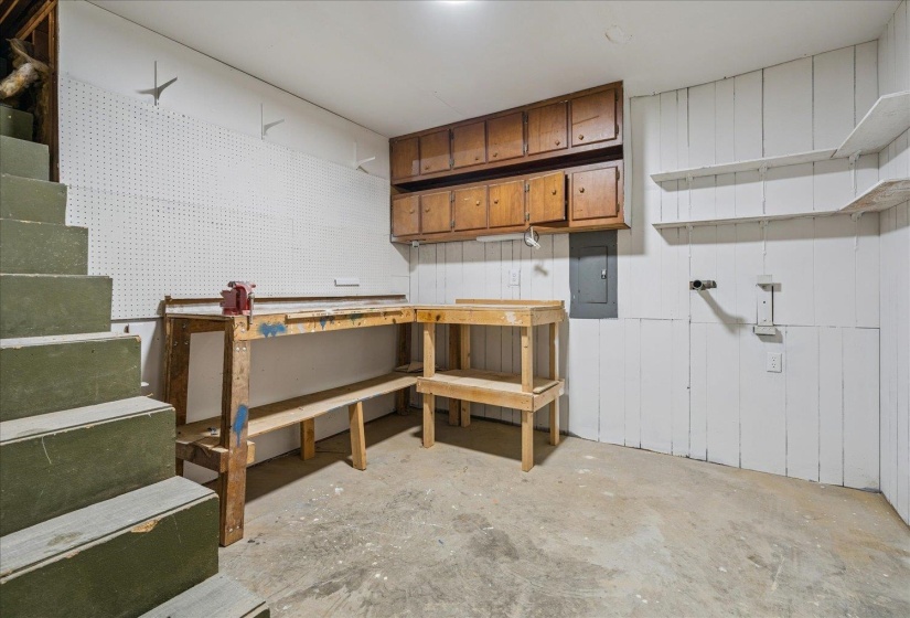Utility room featuring a built-in workbench, wall-mounted cabinetry, open shelving, and concrete flooring