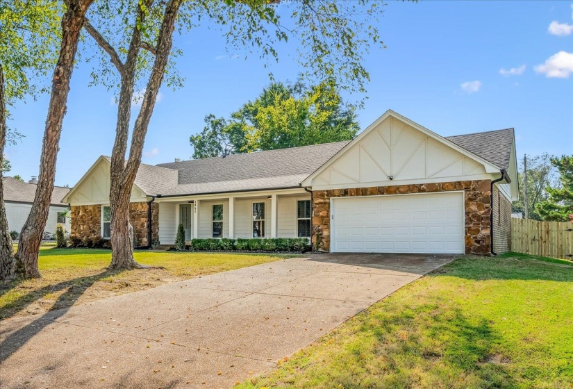 Ranch-style exterior featuring a blend of stone and siding, a two-car garage, a covered front porch with white columns, and a concrete driveway
