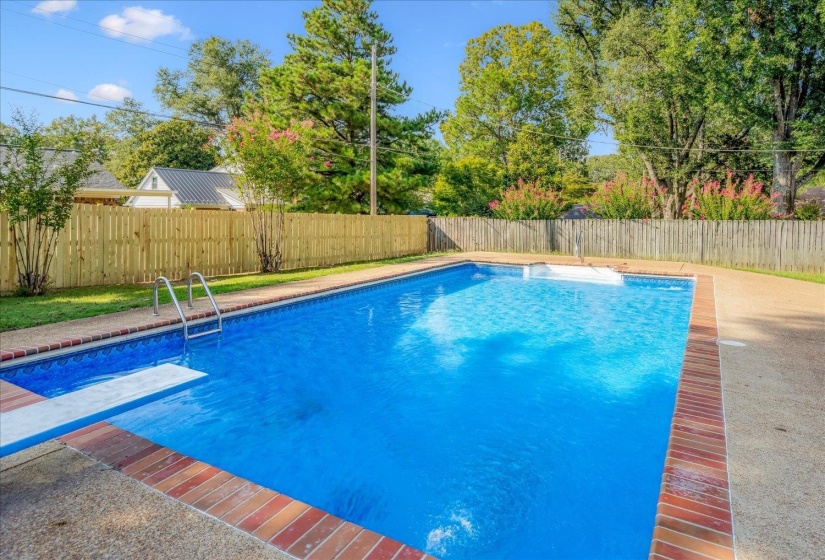 Backyard swimming pool featuring a diving board, integrated steps, and brick coping