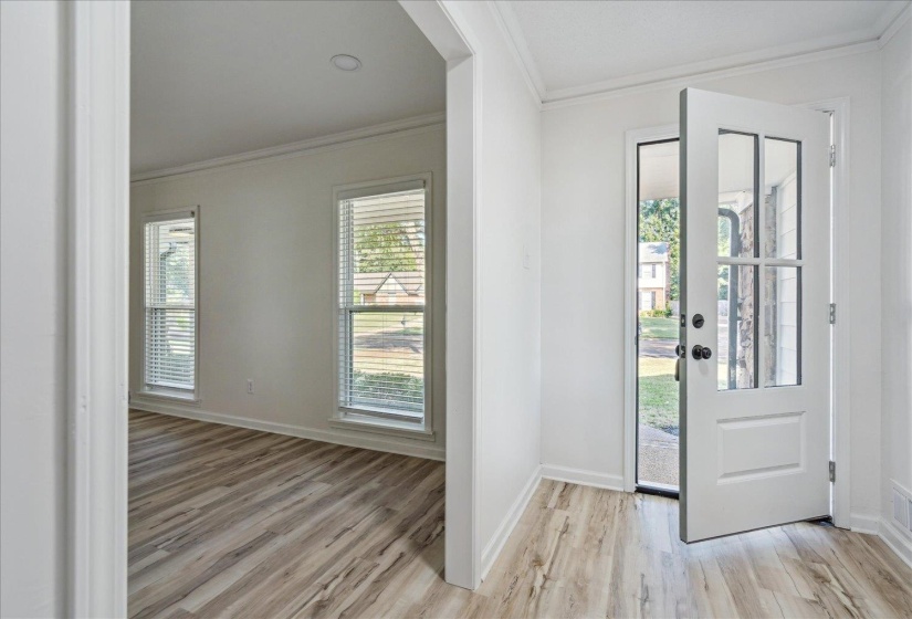 Entryway featuring a paneled glass door, wood-finish flooring, and crisp white trim