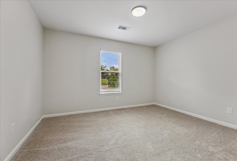 Neutral-toned room featuring a single window with blinds, light-colored walls, and carpet flooring