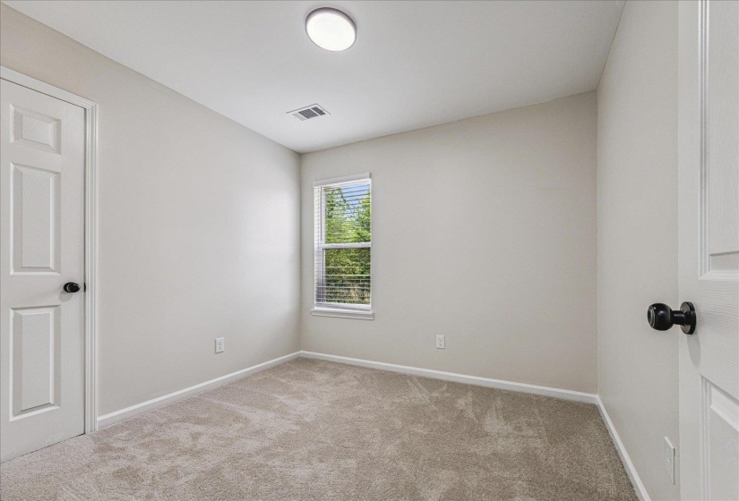 Neutral-toned room featuring light gray walls, plush gray carpeting, and a window with blinds