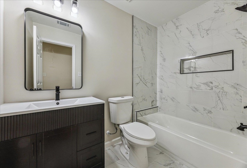 Bathroom featuring a dark wood-finish vanity with an integrated sink, matte black faucet, and a large framed mirror