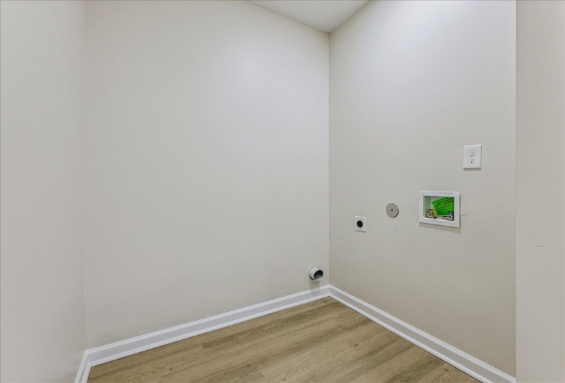 Dedicated laundry space with light wood-finish flooring, white baseboards, and neutral wall paint