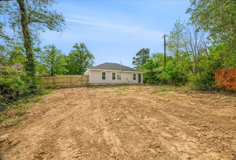 Rear exterior of the property featuring light-colored siding, a dark shingled roof, and multiple windows