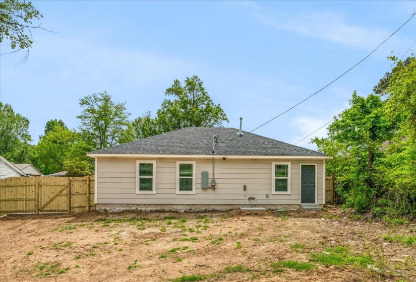 Rear exterior with beige siding and a dark gray shingled roof