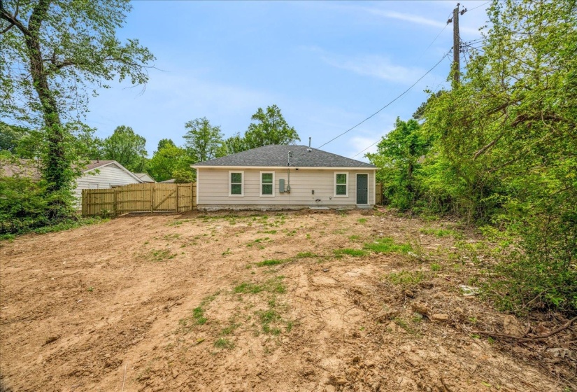 Rear exterior featuring a neutral siding facade, a dark shingle roof, and multiple windows