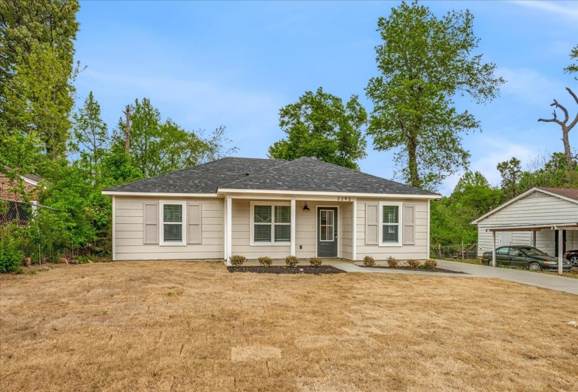 Single-story residence featuring light-colored siding, a dark roof, and a covered front entry