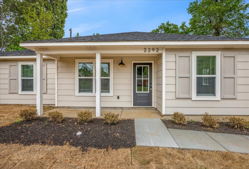 Front exterior with light-toned siding and a dark gray entry door
