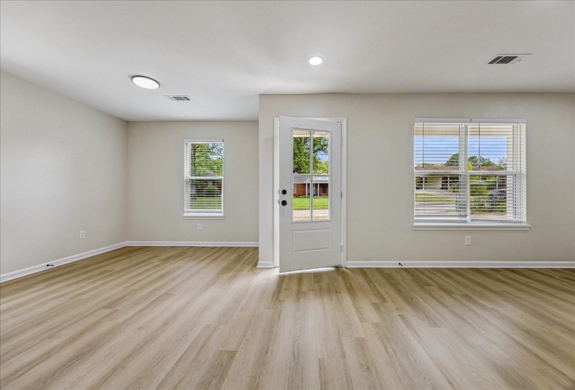 Spacious room featuring light wood-finish flooring, recessed lighting, and a white paneled door with glass inserts