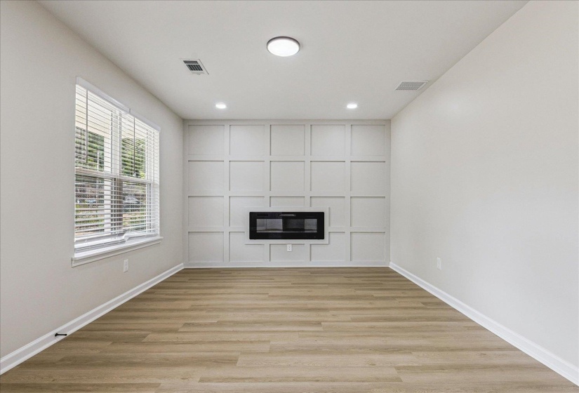 Accent wall featuring a built-in electric fireplace and decorative paneling
