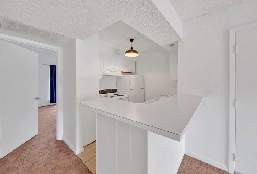 Kitchenette featuring white cabinetry, a white refrigerator, and a built-in range