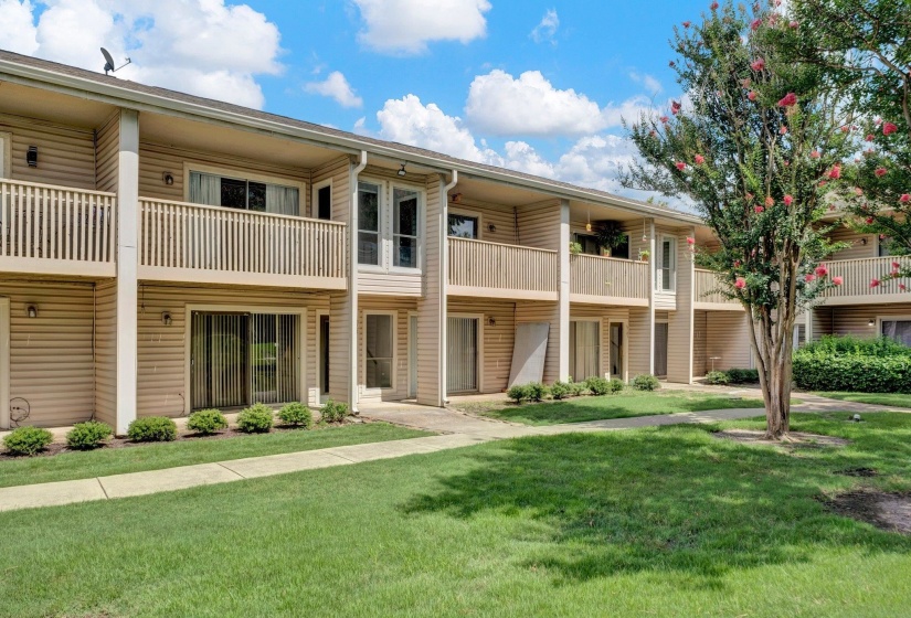 Multi-level residential building featuring tan siding and private balconies with wood railings