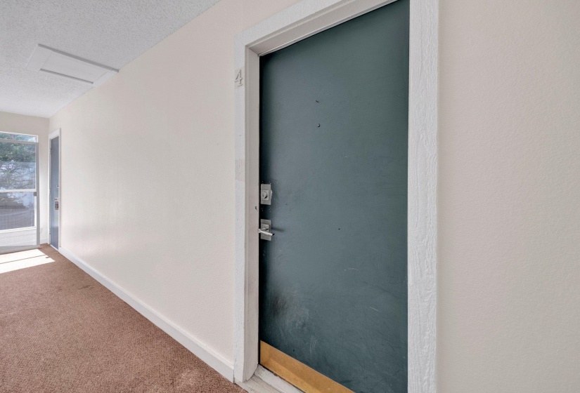 Entryway featuring a dark-colored door with silver-tone hardware, white trim, and light beige wall finishes