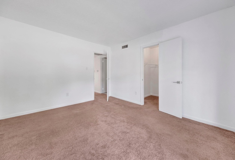Carpeted room featuring white walls, a closet with white bi-fold doors, and a doorway leading to an interior space