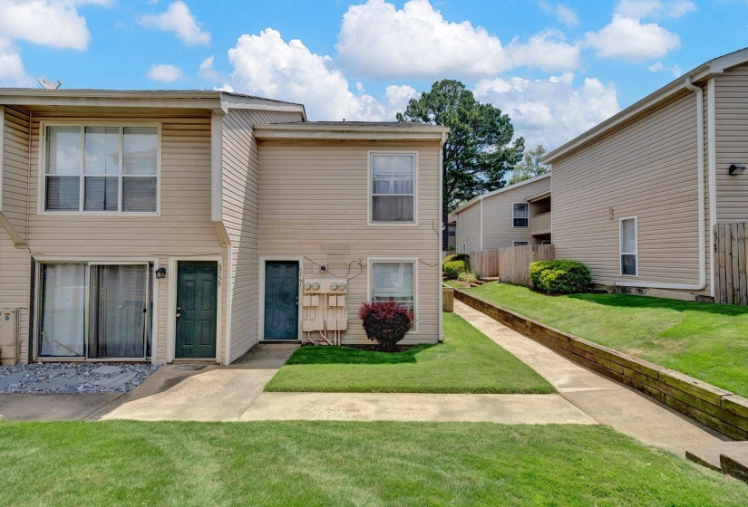 Two-story residential structure featuring beige siding and a dark green entry door