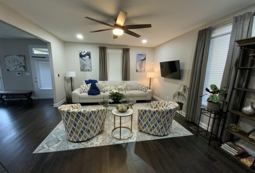 Spacious living area featuring dark wood-finish flooring, recessed lighting, and a ceiling fan with integrated illumination