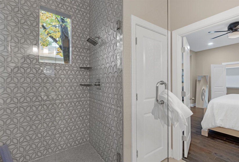 Bathroom featuring a tile shower, wood finished floors, ceiling fan, and connected bathroom