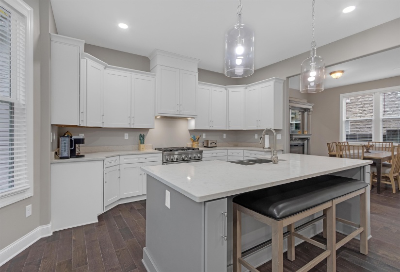 Kitchen featuring a sink, dark wood-style flooring, stove, white cabinets, and a kitchen bar