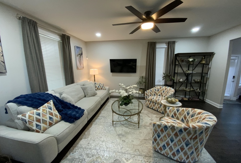 Living area featuring a ceiling fan with integrated lighting, recessed lighting, and dark wood-finish flooring
