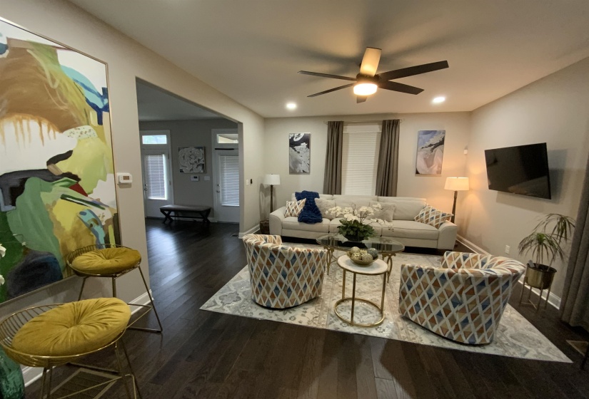 Expansive living area featuring rich, dark wood-finish flooring, recessed lighting, and a ceiling fan