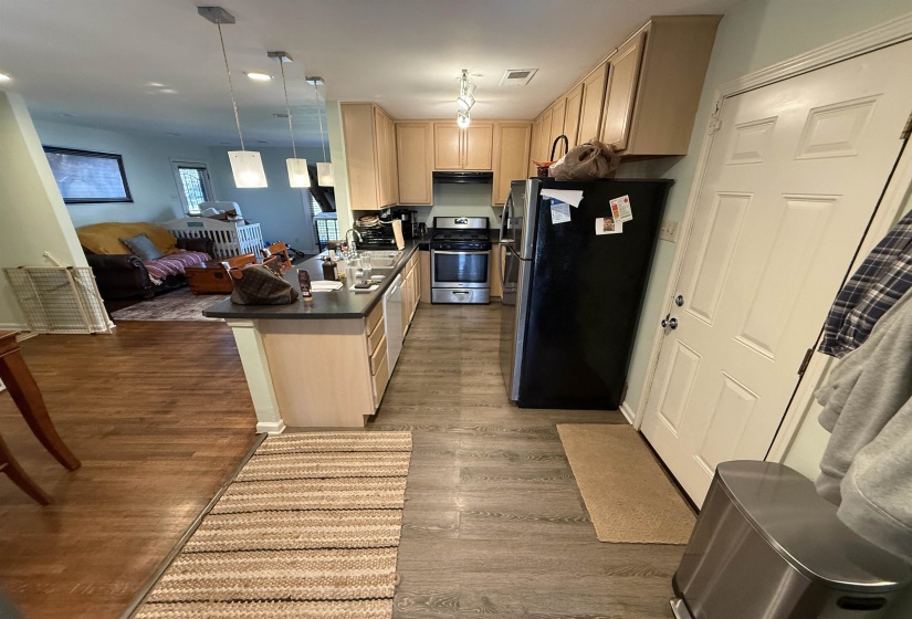 Kitchen featuring light wood finish cabinets, stainless steel appliances, open floor plan, and dark countertops