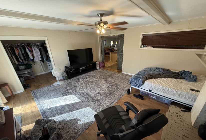 Bedroom featuring beam ceiling, a closet, wood finished floors, and ceiling fan