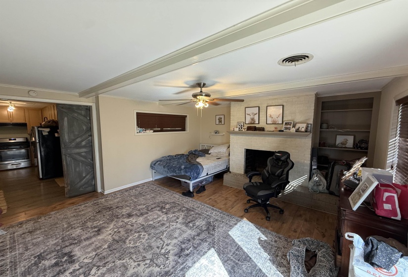 Living room featuring a ceiling fan, built in shelves, dark wood-type flooring, beam ceiling, and crown molding