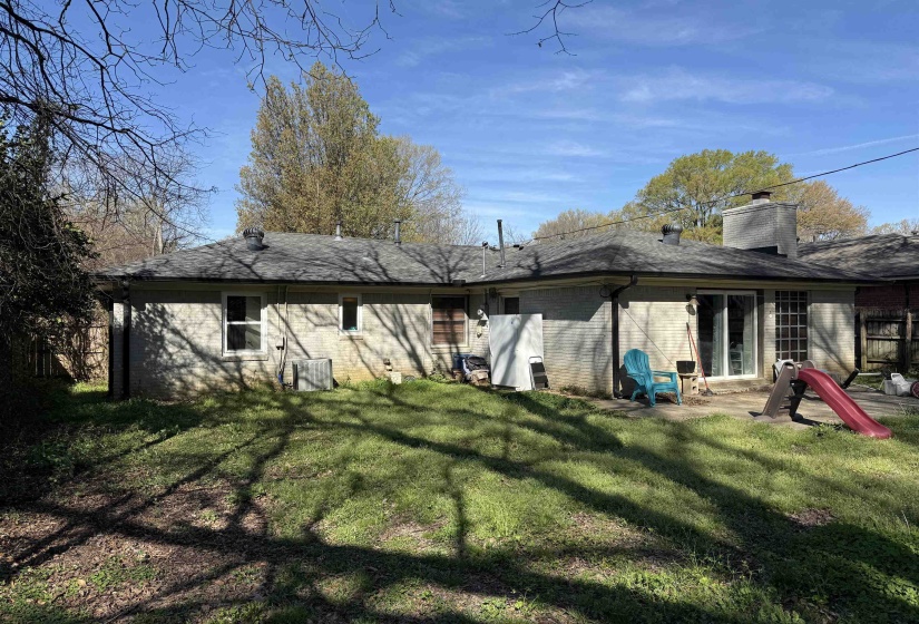 Rear view of house featuring brick siding, a chimney, and a patio area