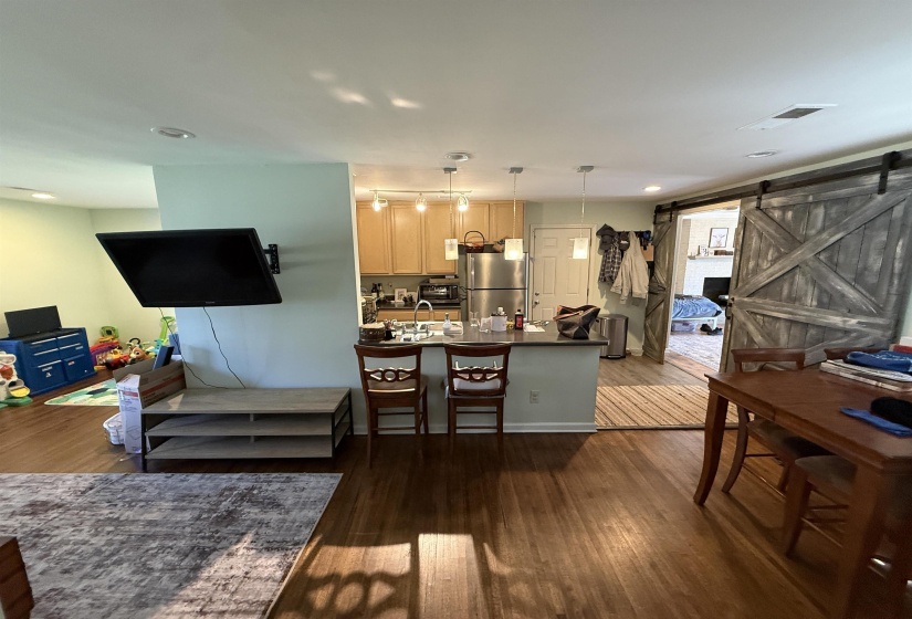 Kitchen featuring a barn door, dark wood-style floors, open floor plan, light wood finish cabinetry, and freestanding refrigerator