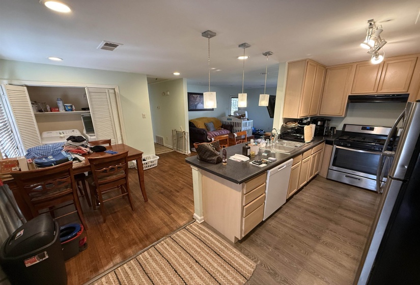 Kitchen with open floor plan, stainless steel appliances, light wood finish cabinetry, and pendant lighting