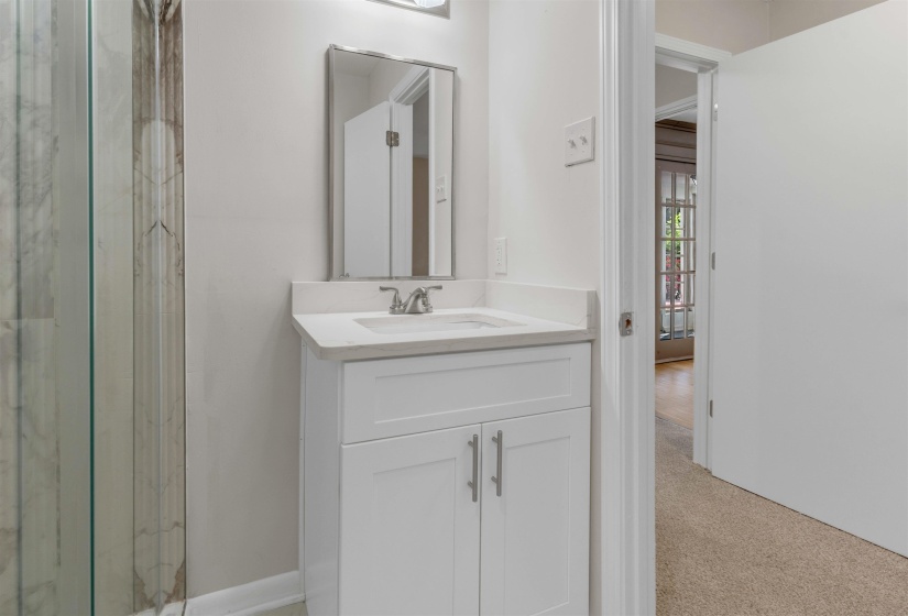 Bathroom vanity featuring a white shaker-style cabinet, a white countertop with an integrated sink, and a framed mirror