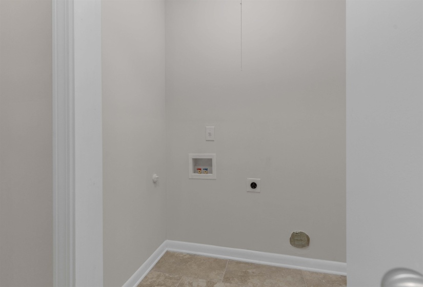 Dedicated laundry area featuring a neutral color palette, durable tile flooring, and integrated washer hookups