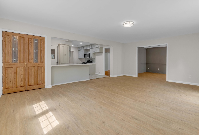 Open-concept living area featuring wood-finish flooring and a recessed kitchen