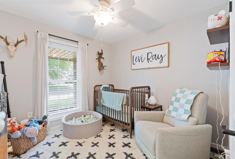 Bright room with a window featuring white blinds and drapes, a ceiling fan with integrated lighting, and light-colored walls