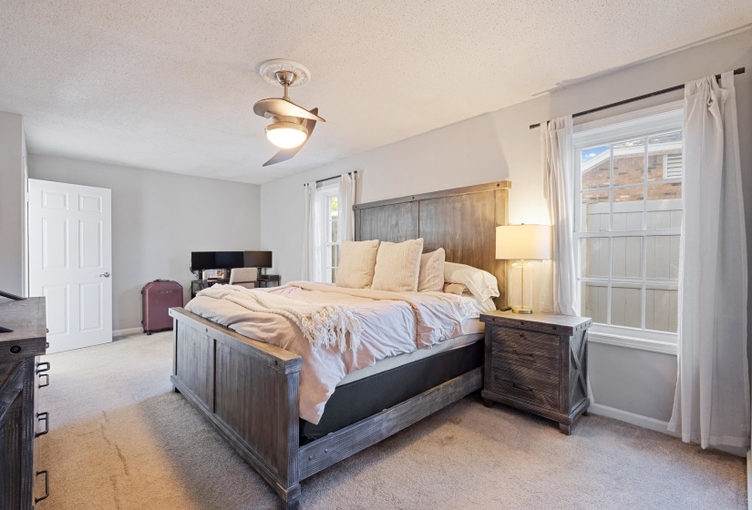 Carpeted interior space featuring a ceiling fan with light fixture, white trim, and a white six-panel door
