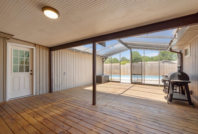 Screened-in patio featuring wood-finish flooring, a white paneled door with glass inserts, and an overhead light fixture